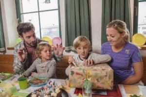 Junge packt Geschenk aus mit seiner Familie
